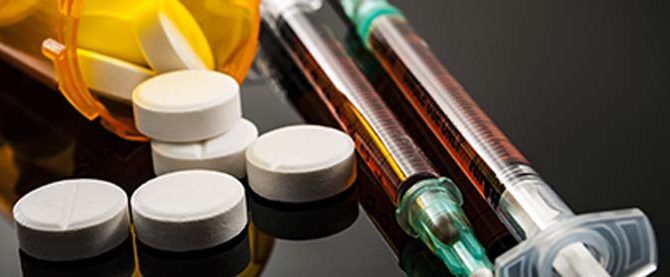 white pills and two syringes filled with brown liquid