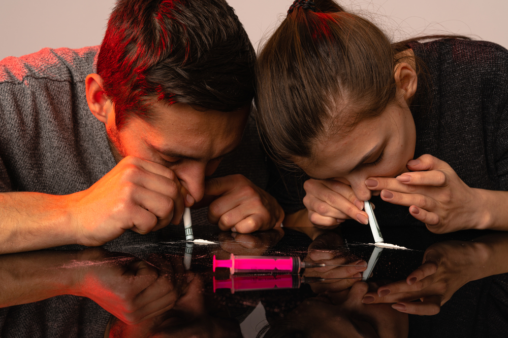 man and woman snorting cocaine lines together