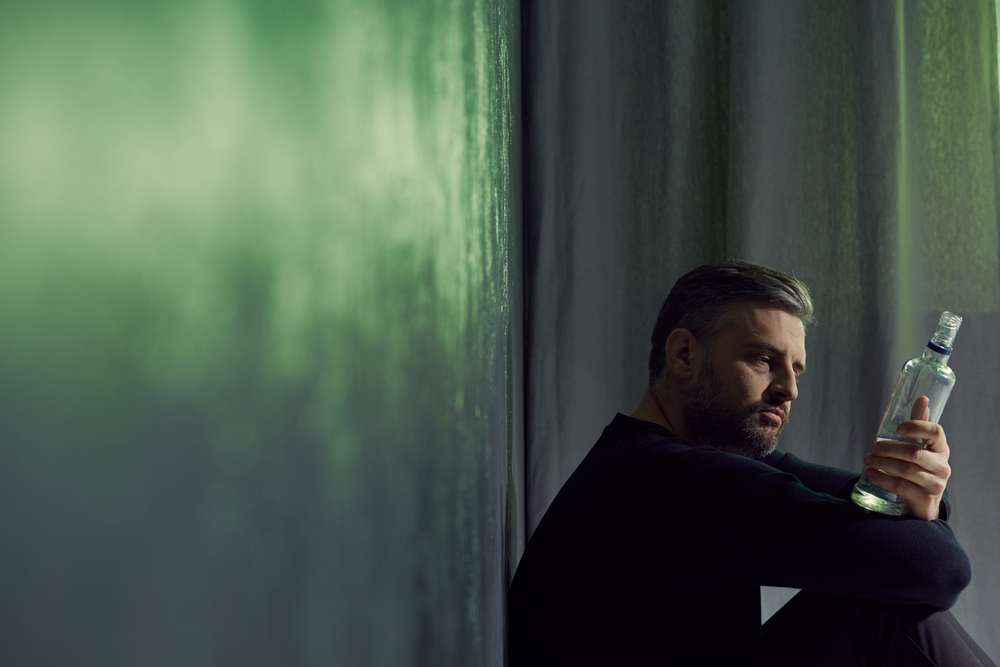 man sitting with alcohol bottle at home